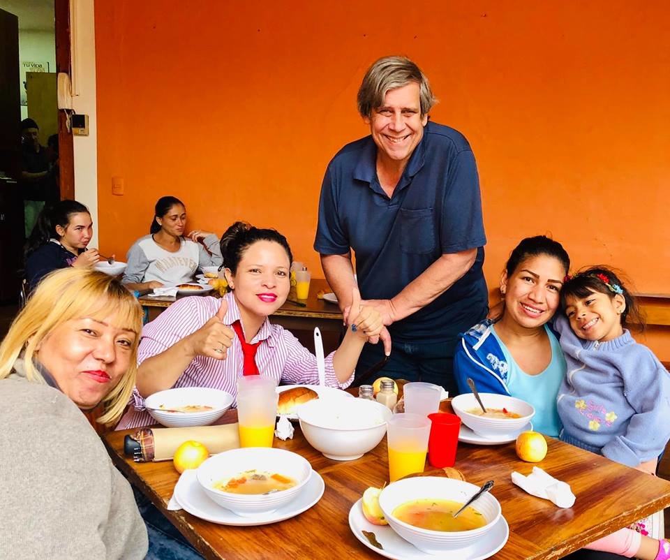 Bob Higgins, Executive Director and Founder of the Cuenca Soup Kitchen, serving a hungry Venezuelan family a hot lunch.